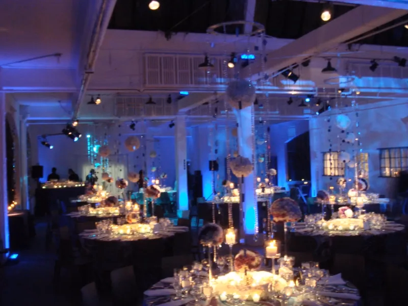 Elegant reception tables with candlelight and blue uplighting in a grand event room